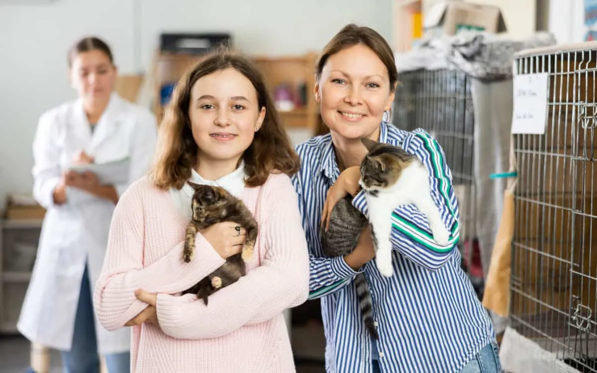 Šťastná nedospělá dívka a její matka stojící v útulku pro opuštěná zvířata' title=