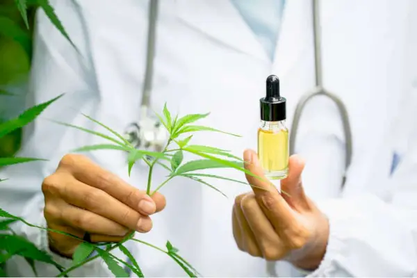 Personne en blouse de laboratoire tenant un compte-gouttes d'huile de CBD