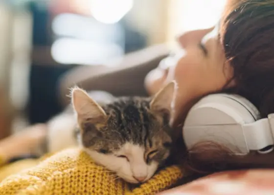 Das Bild zeigt eine Frau und ihre Katze, die gemeinsam Musik hören.