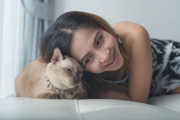 Mujer y gato recostados en el sofá.