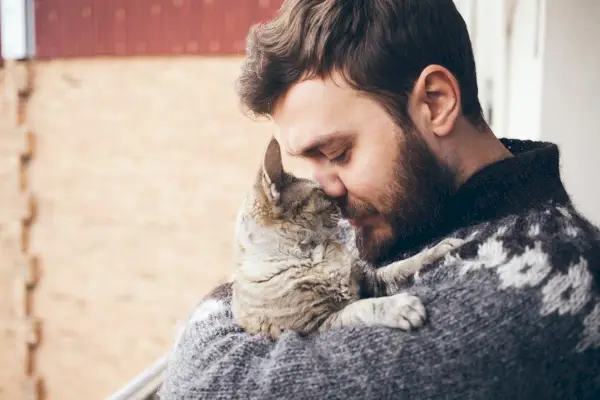 portrett av glad katt med lukkede øyne og ung mann