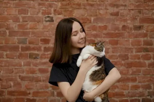 mujer sostiene gato mira hacia otro lado