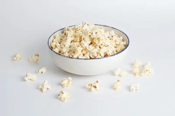 Nieuwsgierige kat aangetrokken door een kom popcorn.