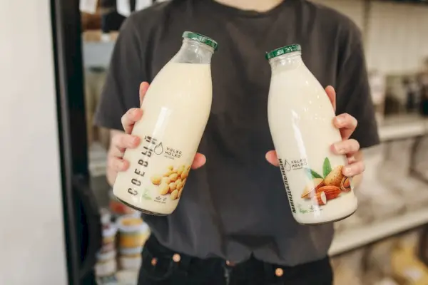 Personne tenant deux bouteilles de lait d'amande