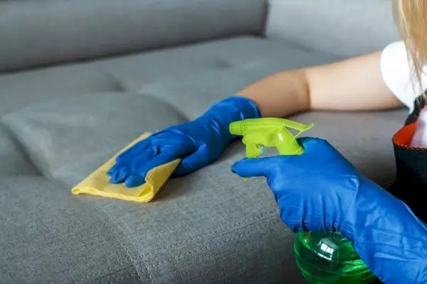 fille aspergeant le canapé avec de l'eau