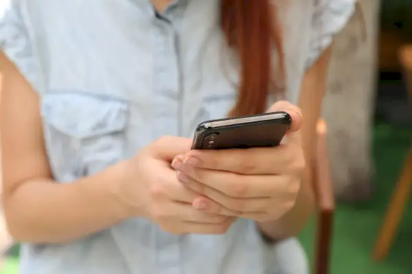 mujer sosteniendo un teléfono móvil