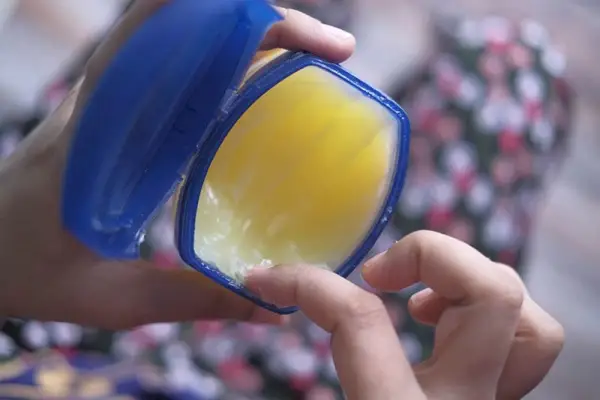 Mit der Hand etwas Vaseline aus dem Glas schöpfen